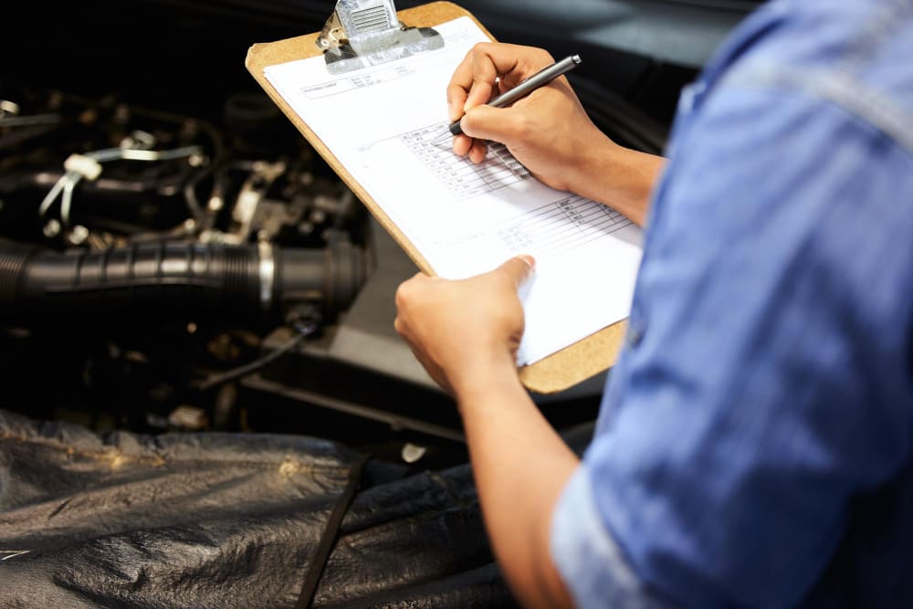 A man is doing an under-hood inspection of his truck